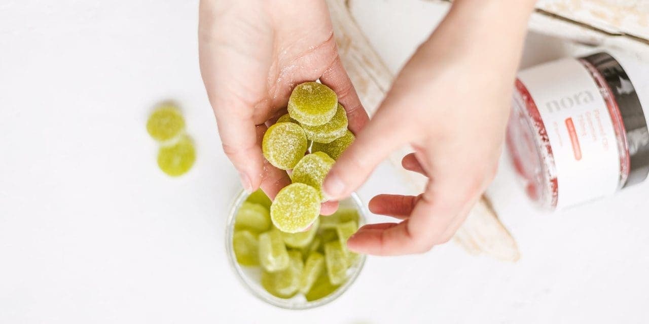 closeup pair of hands holding a handful green cannabis edibles