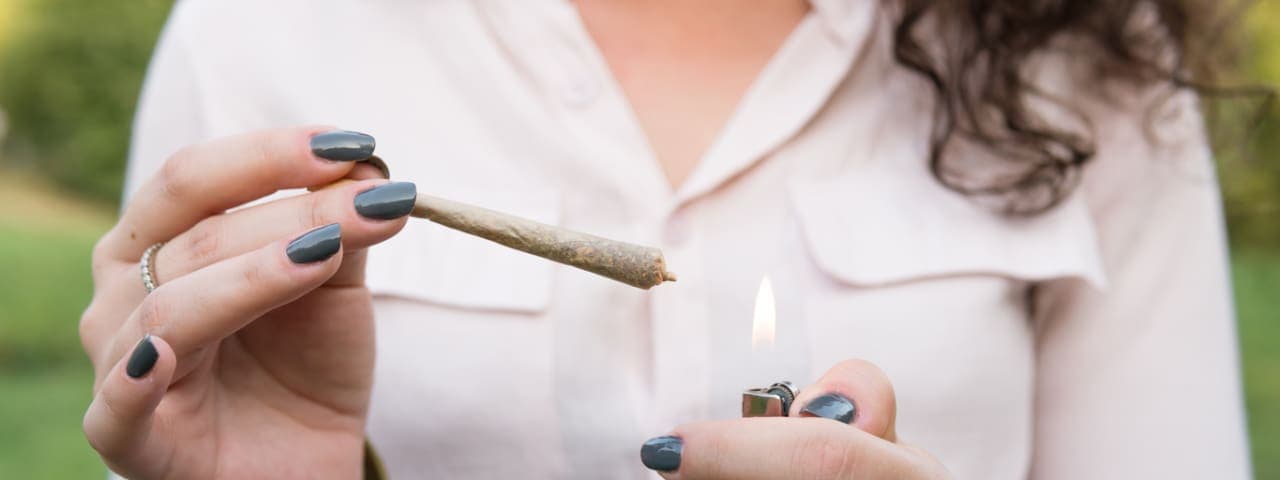 A woman's hands lighting a cannabis pre-roll